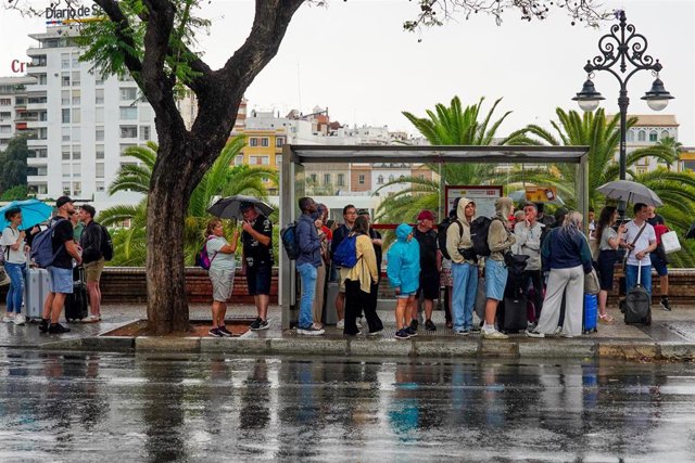 Archivo - Turistas refugiados por la lluvia en una parada de autobús, a 18 de mayo de 2023, en Sevilla, (Andalucía, España). (Foto de archivo).