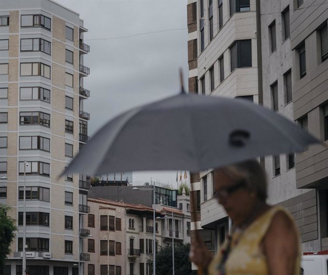 Una mujer camina bajo la lluvia, archivo 