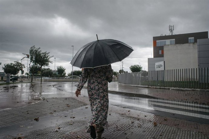 Una mujer camina bajo la lluvia, archivo 