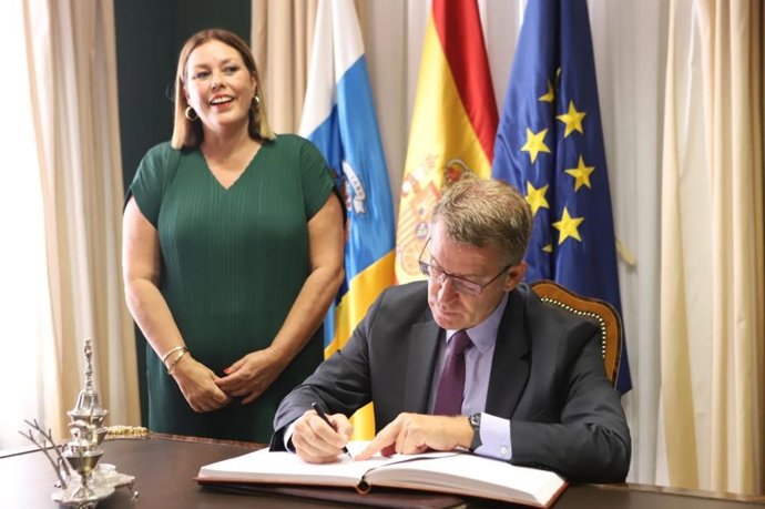 La presidenta del Parlamento de Canarias, Astrid Pérez, contempla como el presidente del PP, Alberto Núñez Feijóo, firma en el Libro de Honor