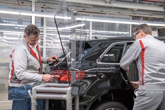 Archivo - Dos trabajadores produciendo un coche en una planta de Audi.