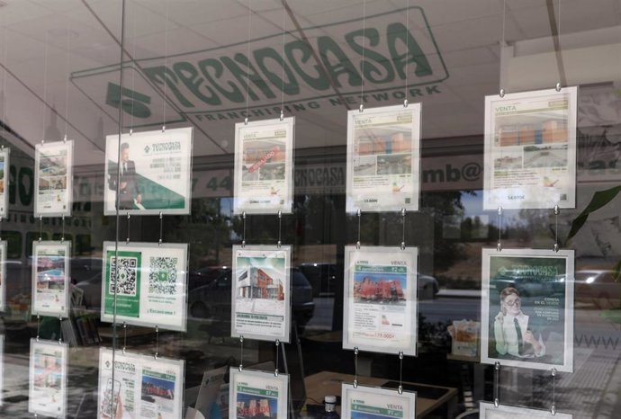 Archivo - Varios carteles de pisos en venta en una oficina de Tecnocasa
