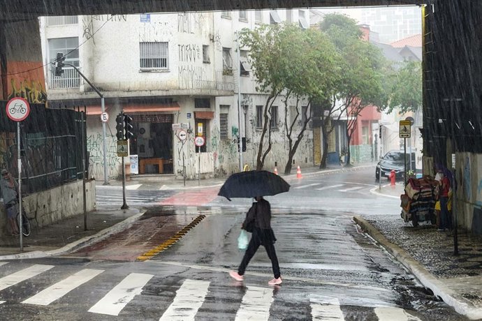 Archivo - 10 March 2023, Brazil, Sao Paulo: Aperson shields under an umbrella while crossing the road amid heavy rainfall in Sao Paulo. Heavy rainfall hit Sao Paulo causing flood around Bela Vista neighbourhood and affecting the flow of traffic. Photo: