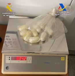 Los 'dátiles' de cocaína incautados en el aeropuerto de Palma sobre una báscula que indica su peso.