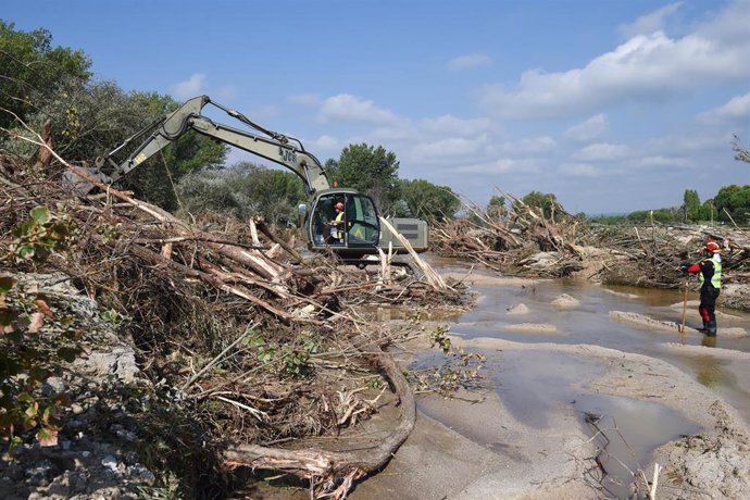 Una máquina excavadora y un trabajador durante el dispositivo de búsqueda de los desaparecidos por las lluvias de La Dana