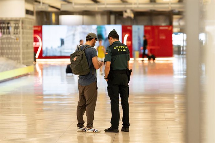 Un pasajero habla con una agente de la Guardia Civil en la T4 el Aeropuerto Adolfo Suárez Madrid-Barajas