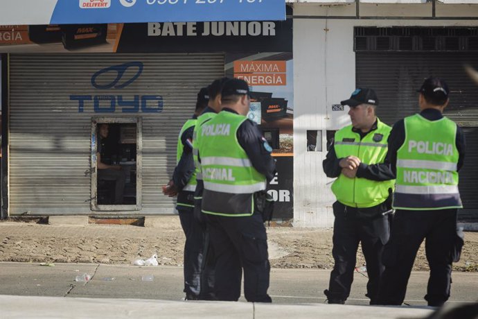 Archivo - May 11, 2023, Asuncion, Paraguay: A person looks from inside a store that remains partially shuttered as police officers stand guard during a demonstration against the alleged electoral fraud in the recent general elections held on April 30, in 