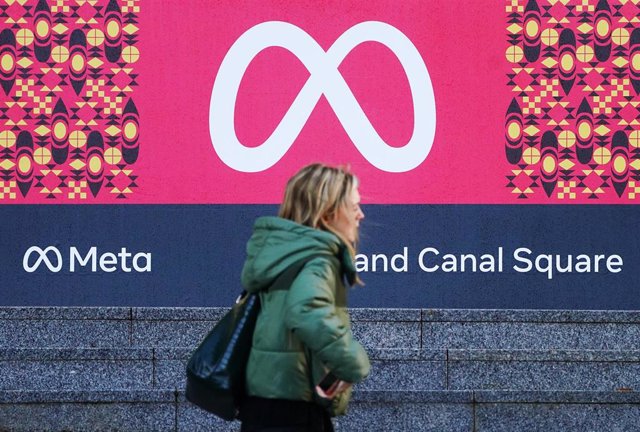 Archivo - Una persona camina delante del logotipo de Meta, empresa matriz de Facebook, en Dublín. 