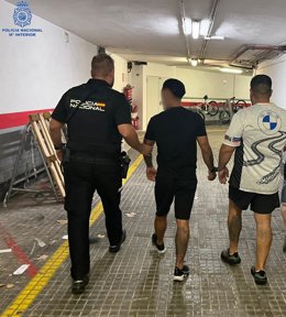 Dos de los detenidos, conducidos por un agente en dependencias policiales.