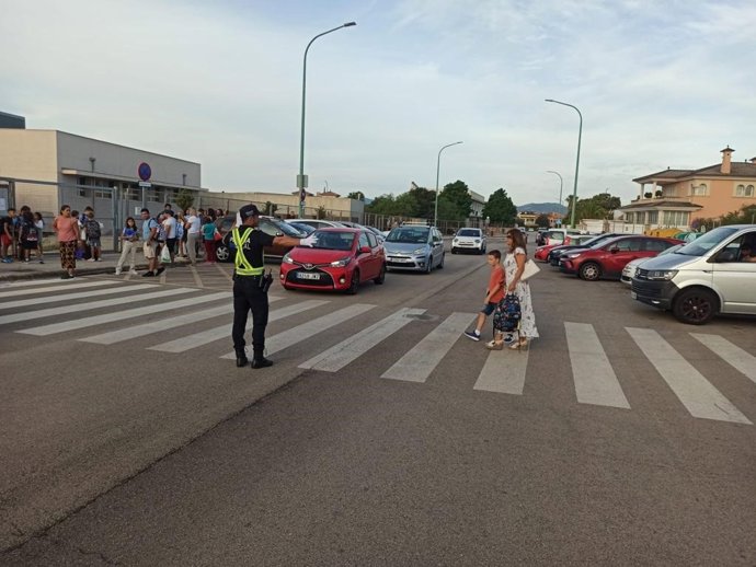 Un niño cruza un paso de peatones en las inmediaciones de un colegio en Marratxí en presencia de un policía local.