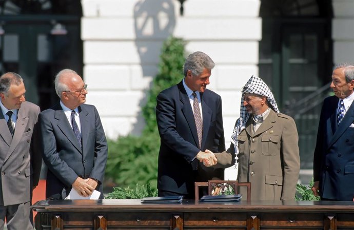 Archivo - El expresidente de EEUU Bill Clinton saluda al presidente palestino Yasir Arafat durante la firma de los Acuerdos de Oslo en 1993, en presencia del primer ministro de Israel Isaac Rabin (centro-izquierda)
