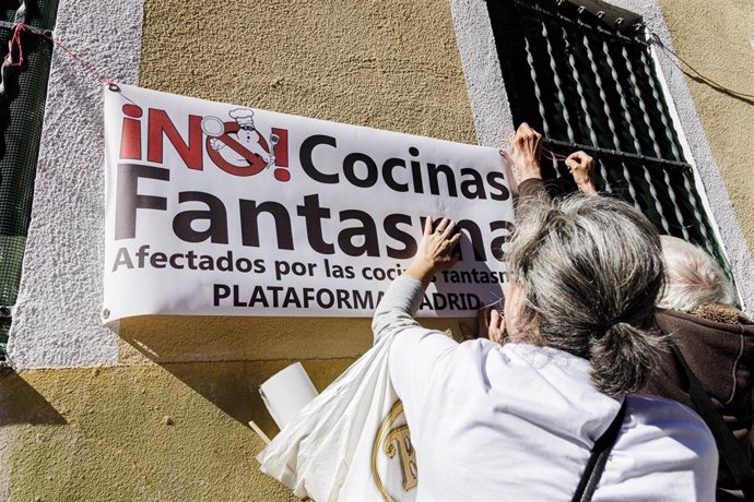 Archivo - Varias personas de agrupaciones vecinales colocan pancartas durante una protesta contra las Cocinas Fantasma 