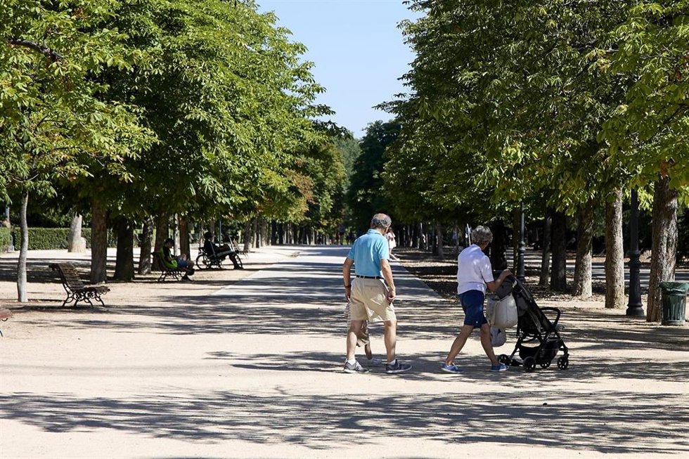 Archivo - Varias personas pasean con un carrito de bebé en el parque de El Retiro.