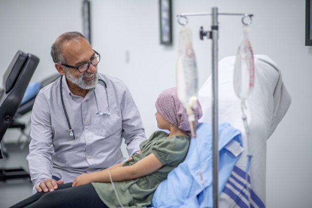 Archivo - An elementary aged girl wearing a head scarf is seen by a medical practitioner.