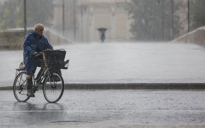 Una persona en bicicleta bajo la lluvia, este viernes en Valncia