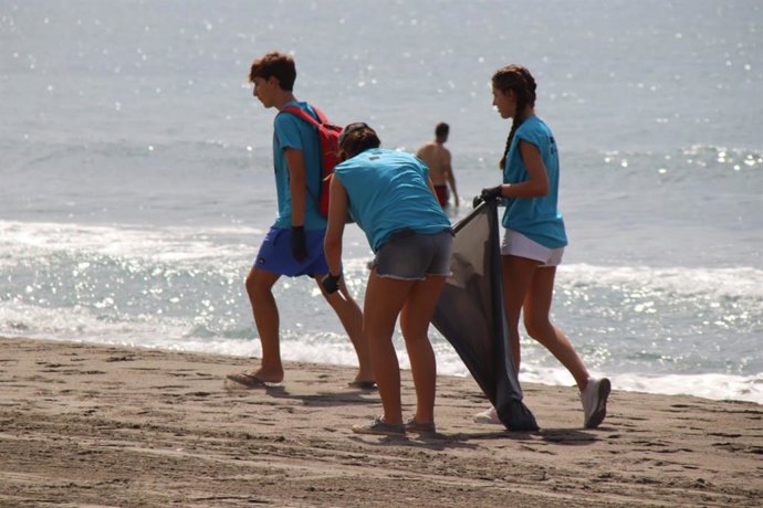 Jóvenes cordobeses retiran basura de la playa malagueña de El Morche.