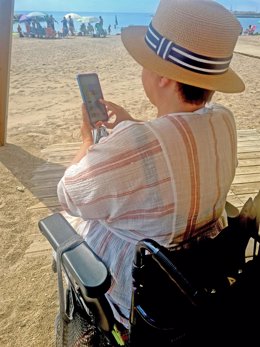 Una mujer en una silla de ruedas en una playa a la que no puede acceder.