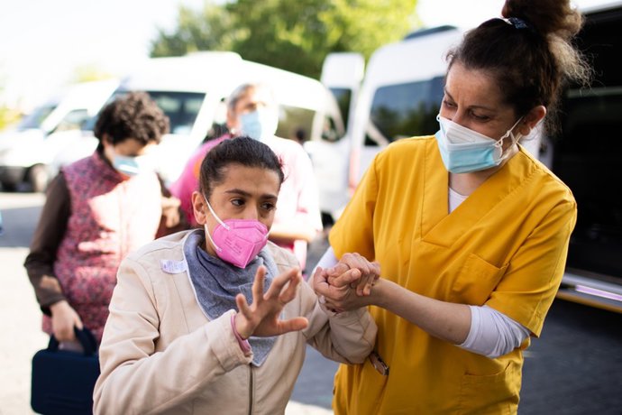 Archivo - Un trabajador atiende a una persona con parálisis cerebral