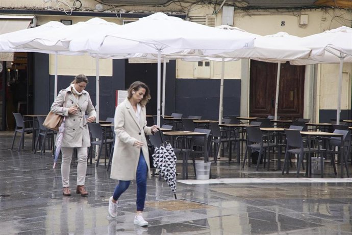 Archivo - Varias personas pasan por una plaza con veladores vacíos, en foto de archivo. 