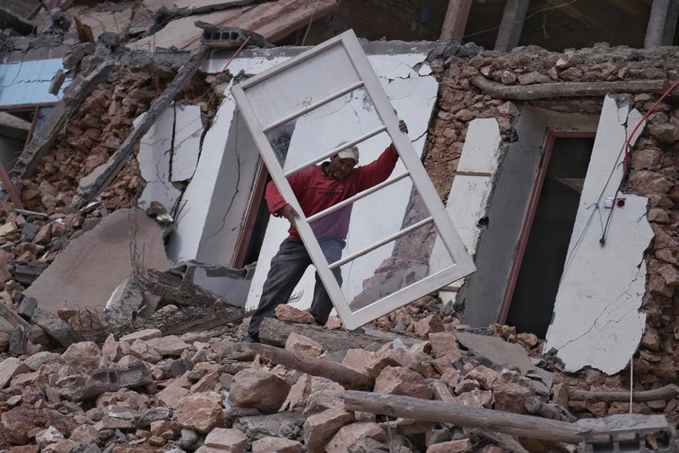Un hombre recupera una puerta acristalada entre los escombros de la aldea desaparecidaen Imi NTala