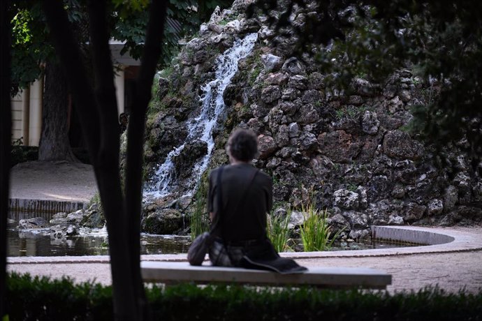 Archivo - Una persona sentada frente a la cascada de los jardines de Vista Alegre en Carabanchel