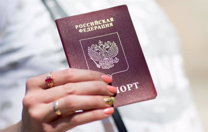 Archivo - Una mujer sostiene un pasaporte ruso.