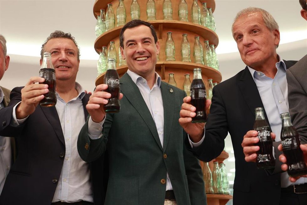 El presidente de la Junta de Andalucía, Juanma Moreno (c), el alcalde de la Rinconada y el presidente de la Diputación de Sevilla, Javier Fernández (i), y el director general de CCEP Iberia, Francesc Cosano (d), en el acto del 25 aniversario de Coca Col