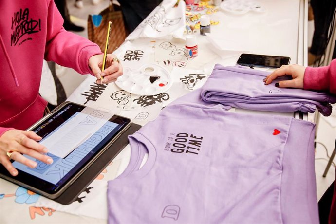 Archivo - Dos personas estampan dibujos y frases en una sudaders.