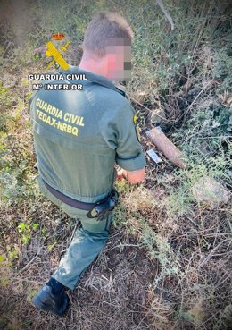 Un agente del TEDAX de la Guardia Civil junto al proyectil de artillería de la Guardia Civil hallado en Zarza Capilla.
