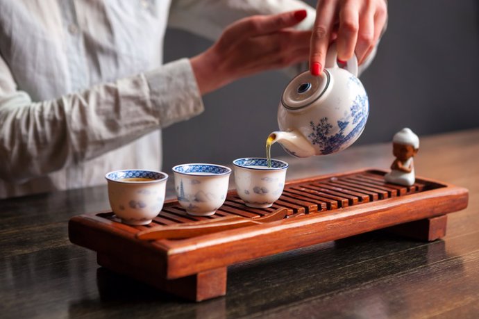 Archivo - Una mujer sirviendo té en una tetera tradicional china.