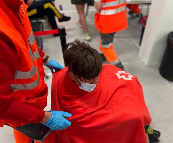 Archivo - Un voluntario de Cruz Roja junto a un inmigrante llegado en patera. Archivo.