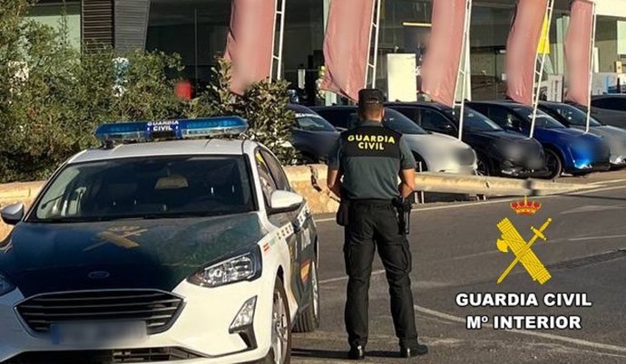 Un agente de la Guardia Civil frente a un concesionario de vehículos.