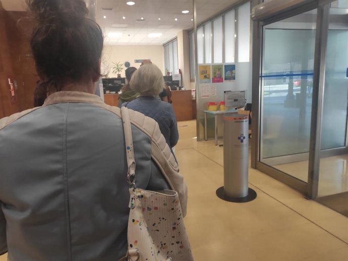 Personas haciendo cola para ser atendidas en el mostrador de un centro de salud.