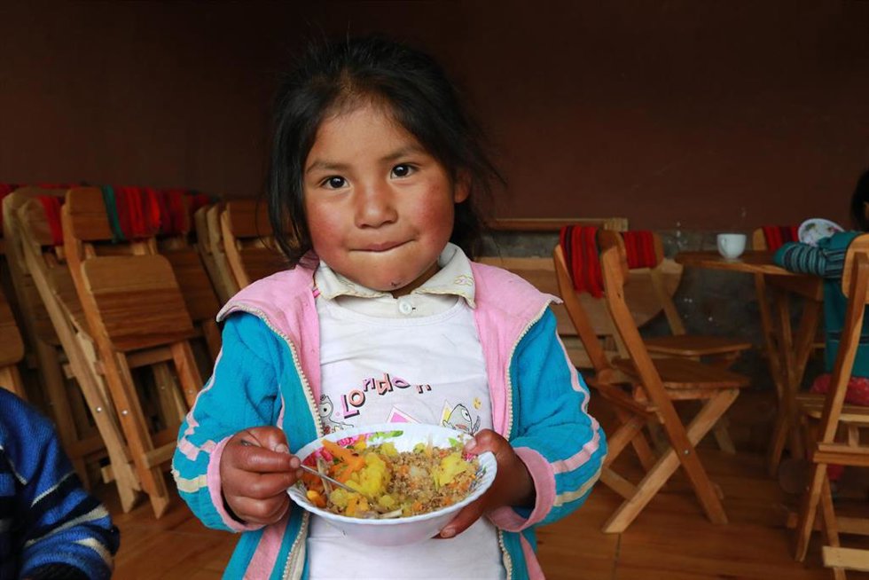 Archivo - Niña con un plato en Perú