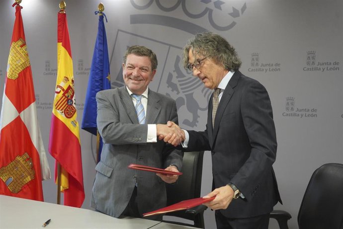 El consejero Luis Miguel González Gago, a la izquierda, estrecha la mano del Fiscal Superior de Castilla y León, Santiago Mena, tras la firma del convenio.