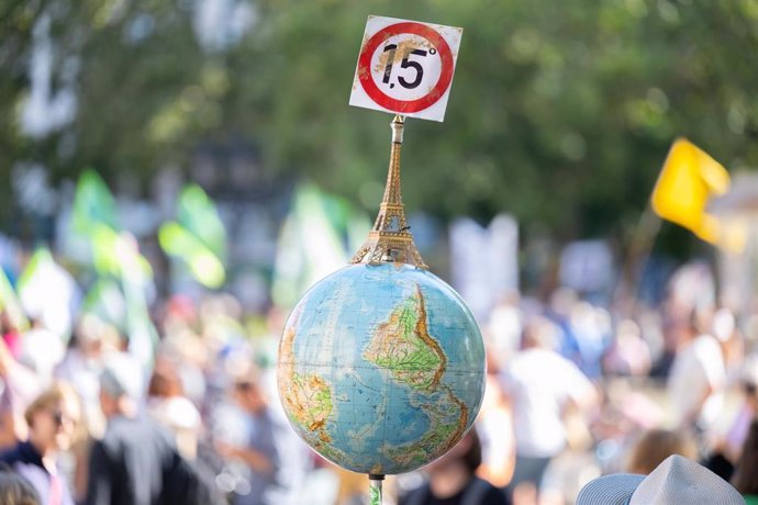 FILED - 15 September 2023, Hesse, Frankfurt_Main: A globe with a miniature Eiffel Tower and the 1.5-degree target of the Paris climate agreement is carried by a protester during a protest organized by the climate protection movement Fridays for Future i