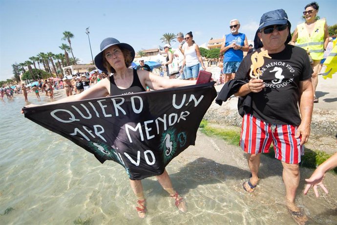 Archivo - Una mujer sujeta un cartel en el que se lee 'Quiero un Mar Menor vivo' tras el abrazo al Mar Menor, a 12 de agosto de 2023, en Murcia, Región de Murcia (España). Hoy se ha formado, por tercer año, una cadena humana para dar un simbólico abrazo