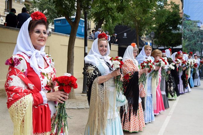 Archivo - Varias mujeres vestidas de chulapas reparten claveles rojos y blancos en Las Vistillas