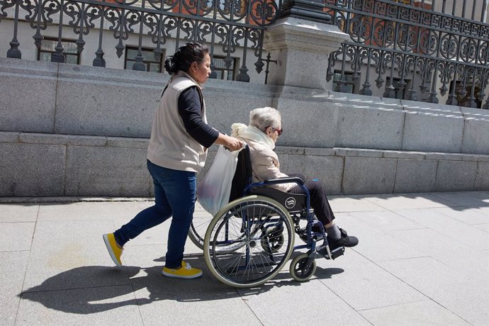 Archivo - Una mujer mayor en silla de ruedas y su cuidadora pasean por el centro de la ciudad, a 4 de junio de 2023, en Madrid (España). La población mayor de 64 años en España supera ya el 20% del total y supera al grupo de personas menor de 20 años,  