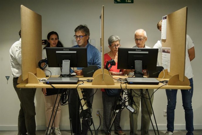 Varias personas votan de forma presencial, en la Cámara de Comercio de Barcelona