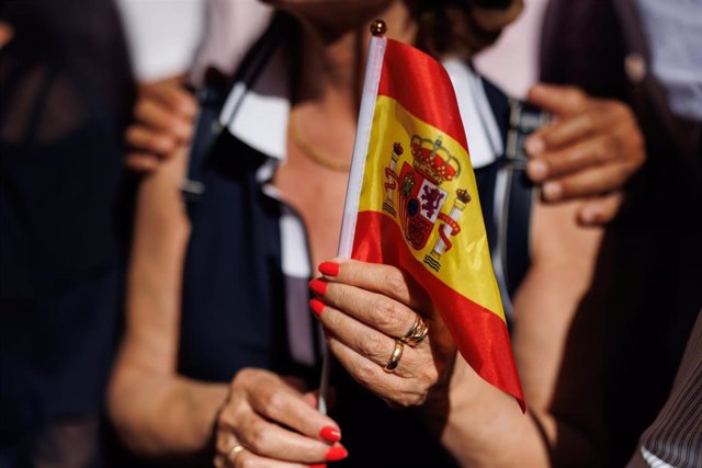 Una persona sujeta un palo enganchado a una bandera de España. 
