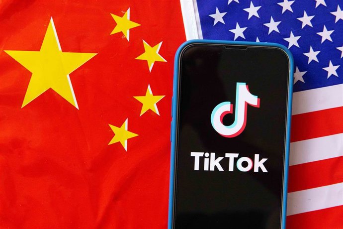 Archivo - Banderas de China y EEUU junto a un teléfono con el logotipo de TikTok
