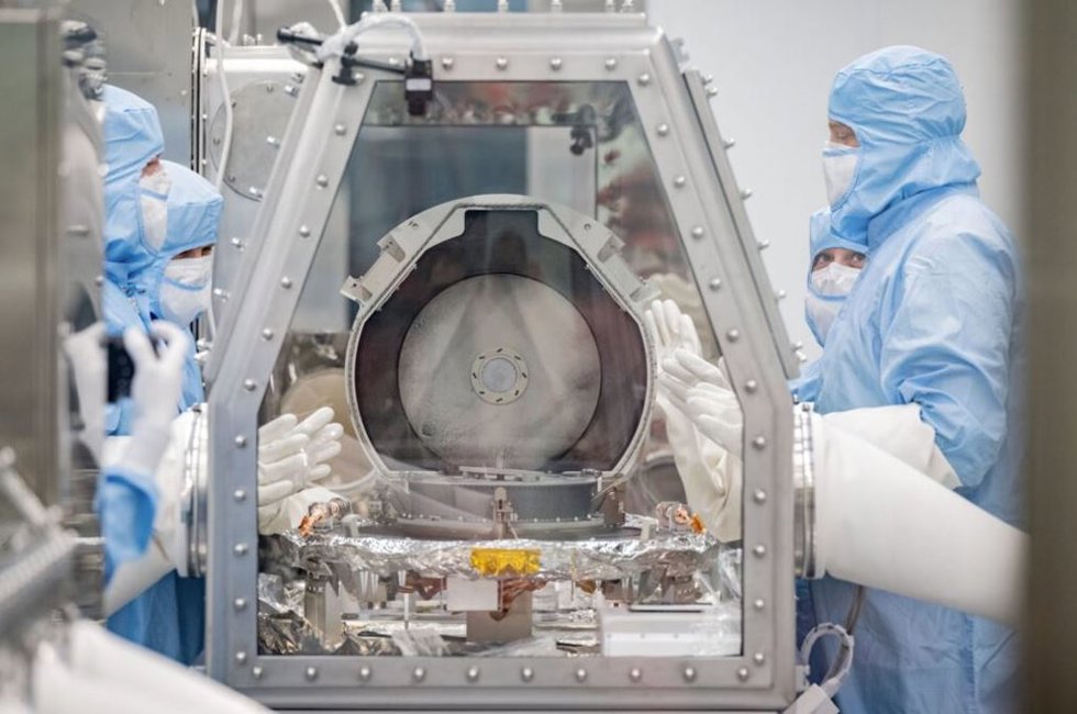 Los miembros del equipo de conservación de la NASA junto con los especialistas en recuperación de Lockheed Martin observan después de retirar con éxito la tapa del recipiente de retorno de muestras.