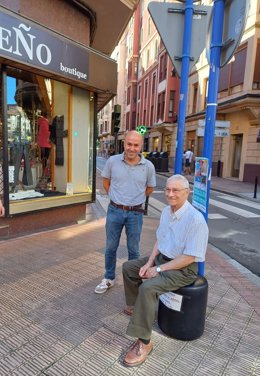 David Solla en el exterior de un comercio con una persona mayor sentada en una silla colocadas por el establecimiento.