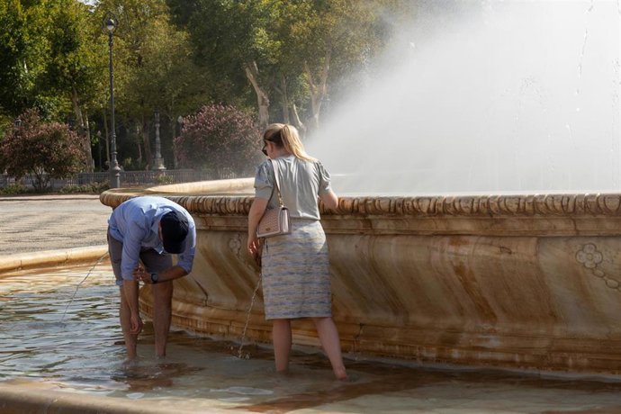 Archivo - Turistas se refrescan en la fuente de la Plaza de España, en plena ola de calor en Sevilla en una imagen de archivo 