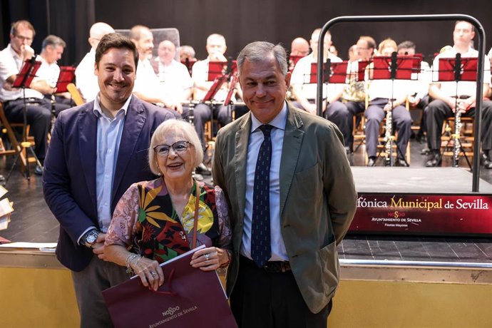 El alcalde de Sevilla, José Luis Sanz, con una de las homenajeadas, en presencia del delegado municipal José Luis García.