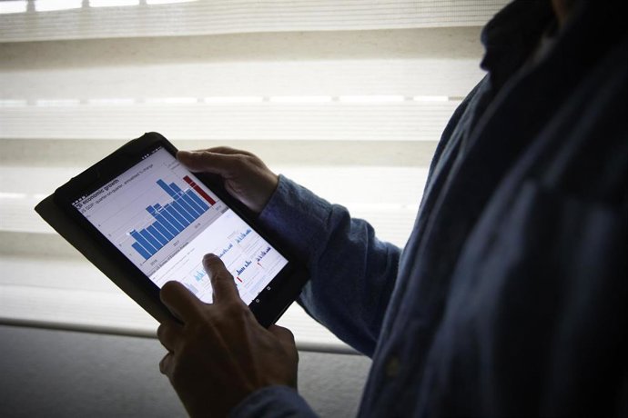 Archivo - Un hombre sujeta una tablet con un gráfico