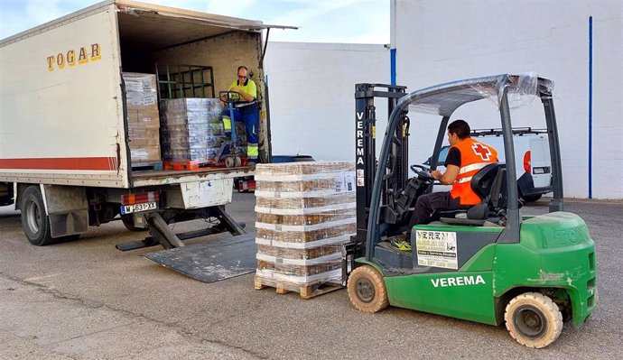 Un voluntario de Cruz Roja carga un camión con los alimentos que se van a repartir.