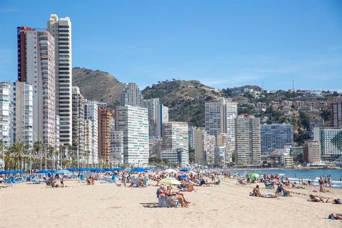 Archivo - Numerosas personas toman el sol y se bañan en la playa de Poniente, en Benidorm, en una imagen de archivo