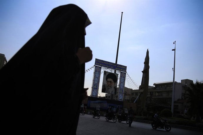 September 26, 2023, Tehran, Iran: An Iranian veiled woman in a black chador moves past an Iranian Sejjil solid-fueled medium-range ballistic missile is pictured next to the portrait of Iranian Supreme Leader Ayatollah Ali Khamenei, during a military exh